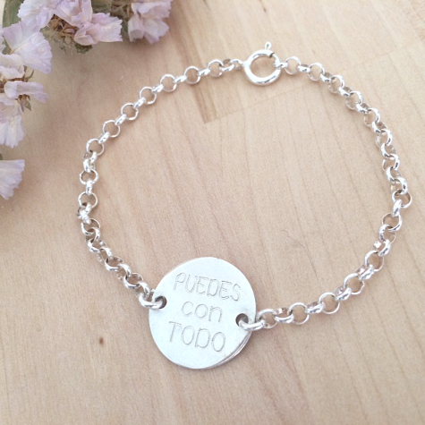 Brazalete de plata con un disco grabado que dice "Puedes con todo".